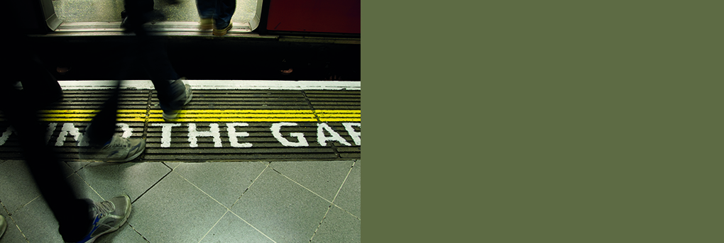 Passengers stepping from platform through train doors, mind the gap text on platform.